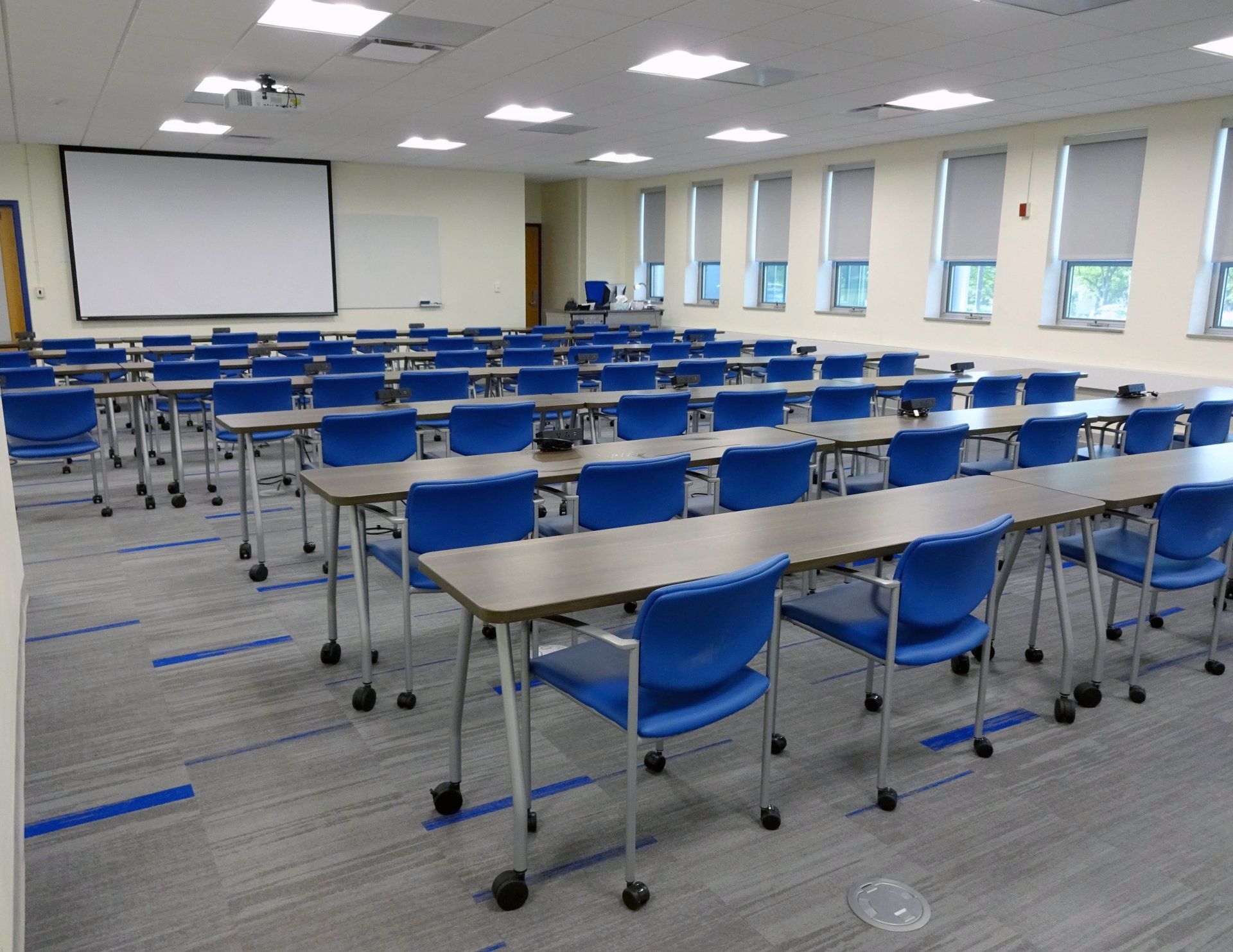 A large room with tables and chairs and a projector screen