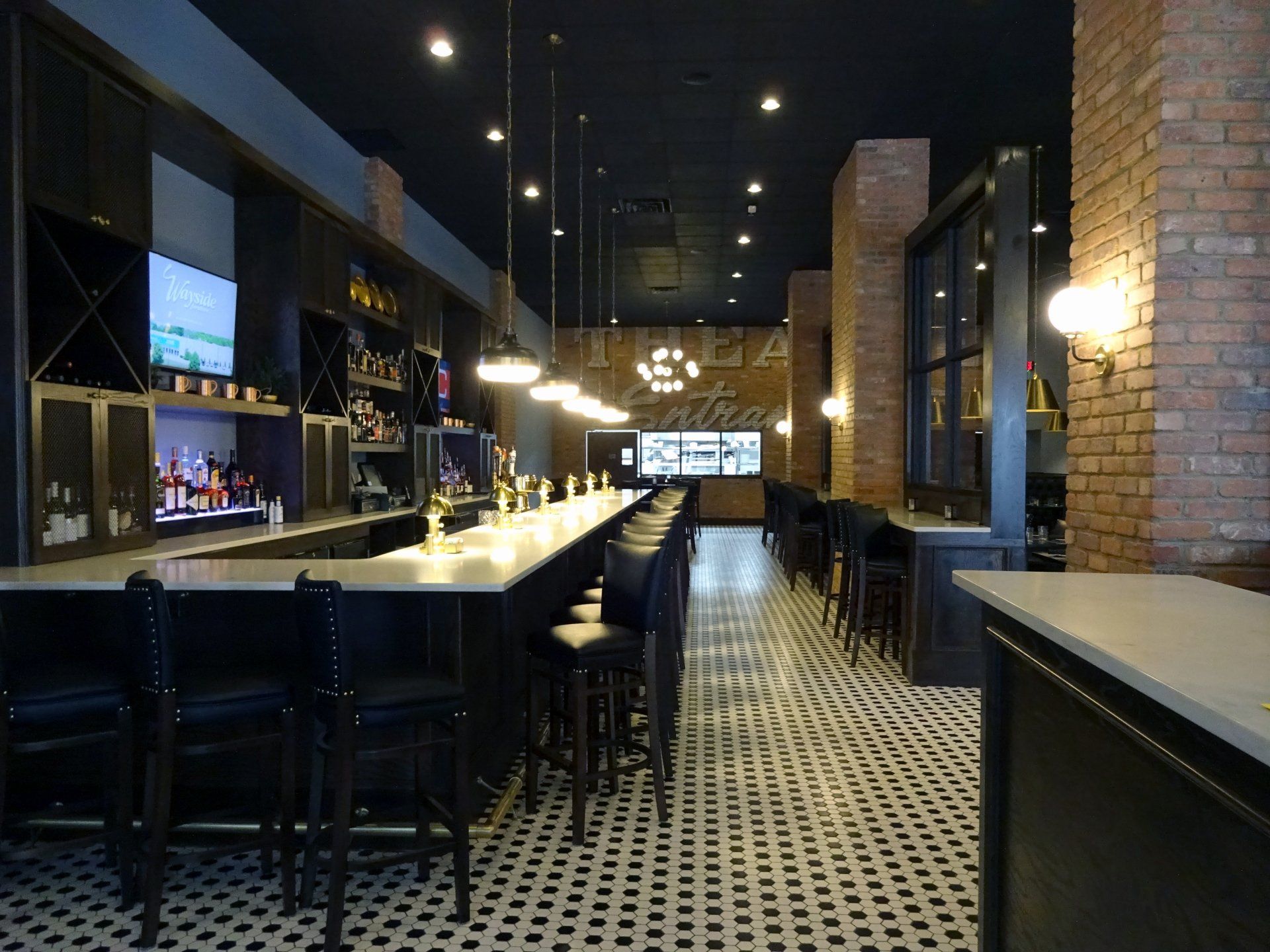 A long bar in a restaurant with a brick wall