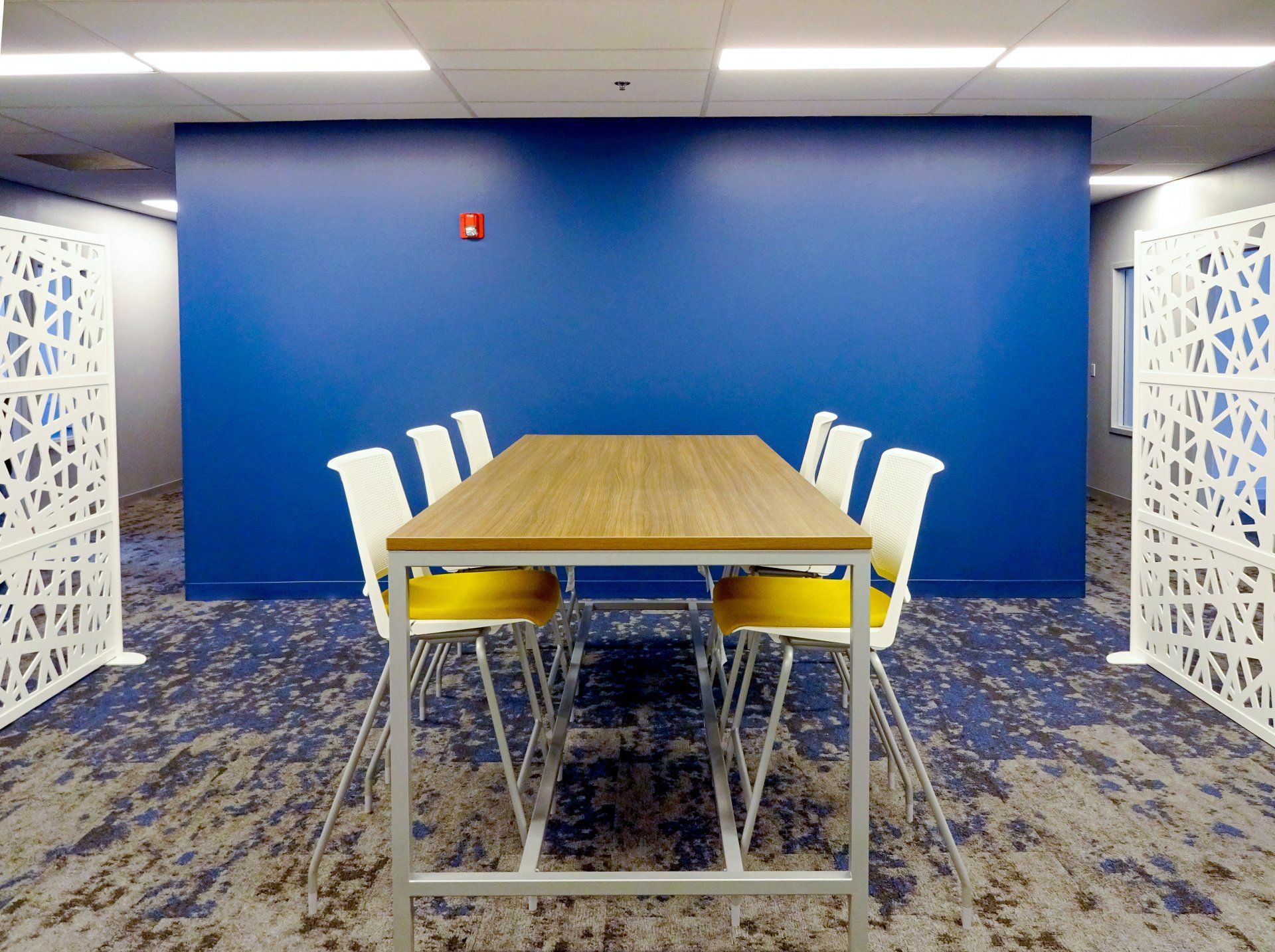 A conference room with a table and chairs in front of a blue wall.
