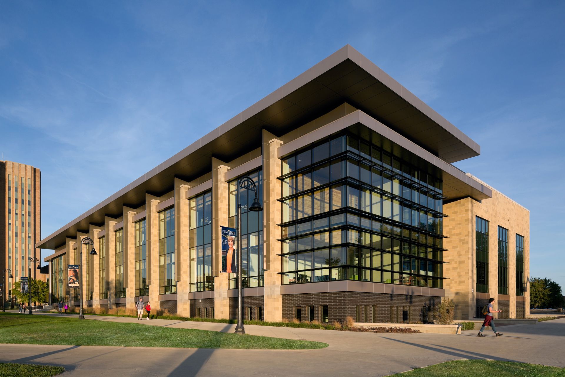 A large brick building with a lot of windows and people walking in front of it.