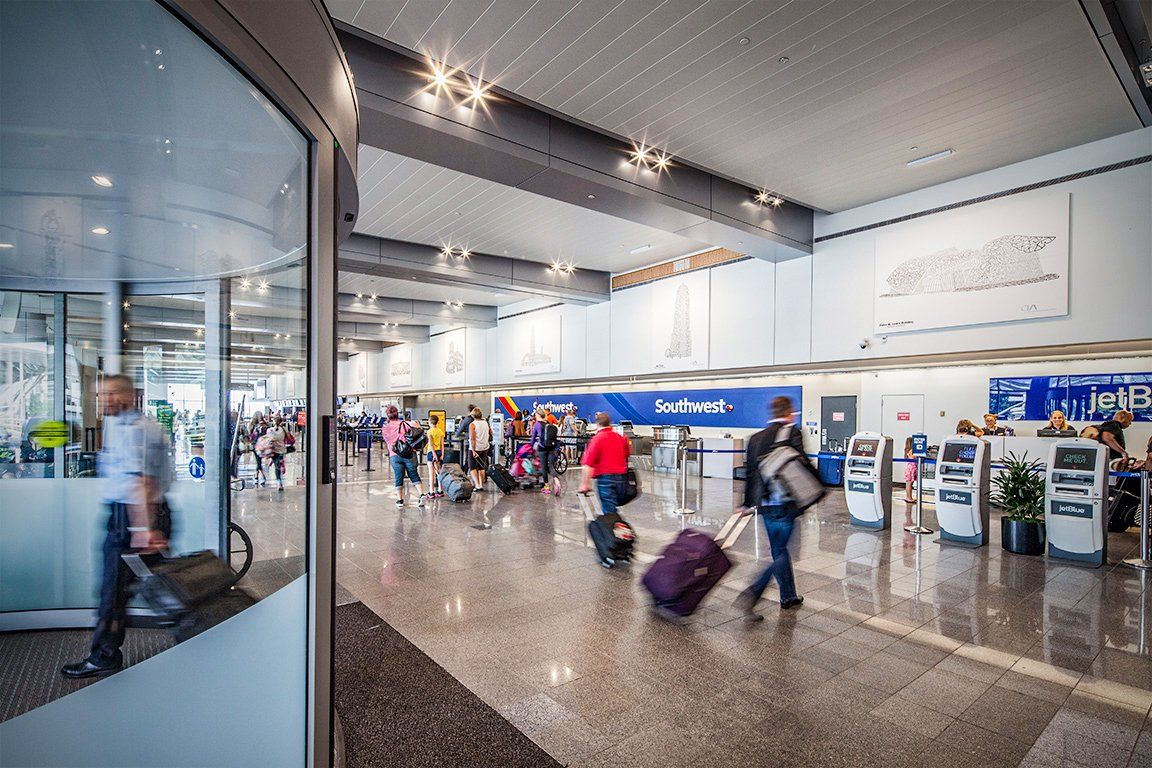 A group of people are walking through an airport with luggage.