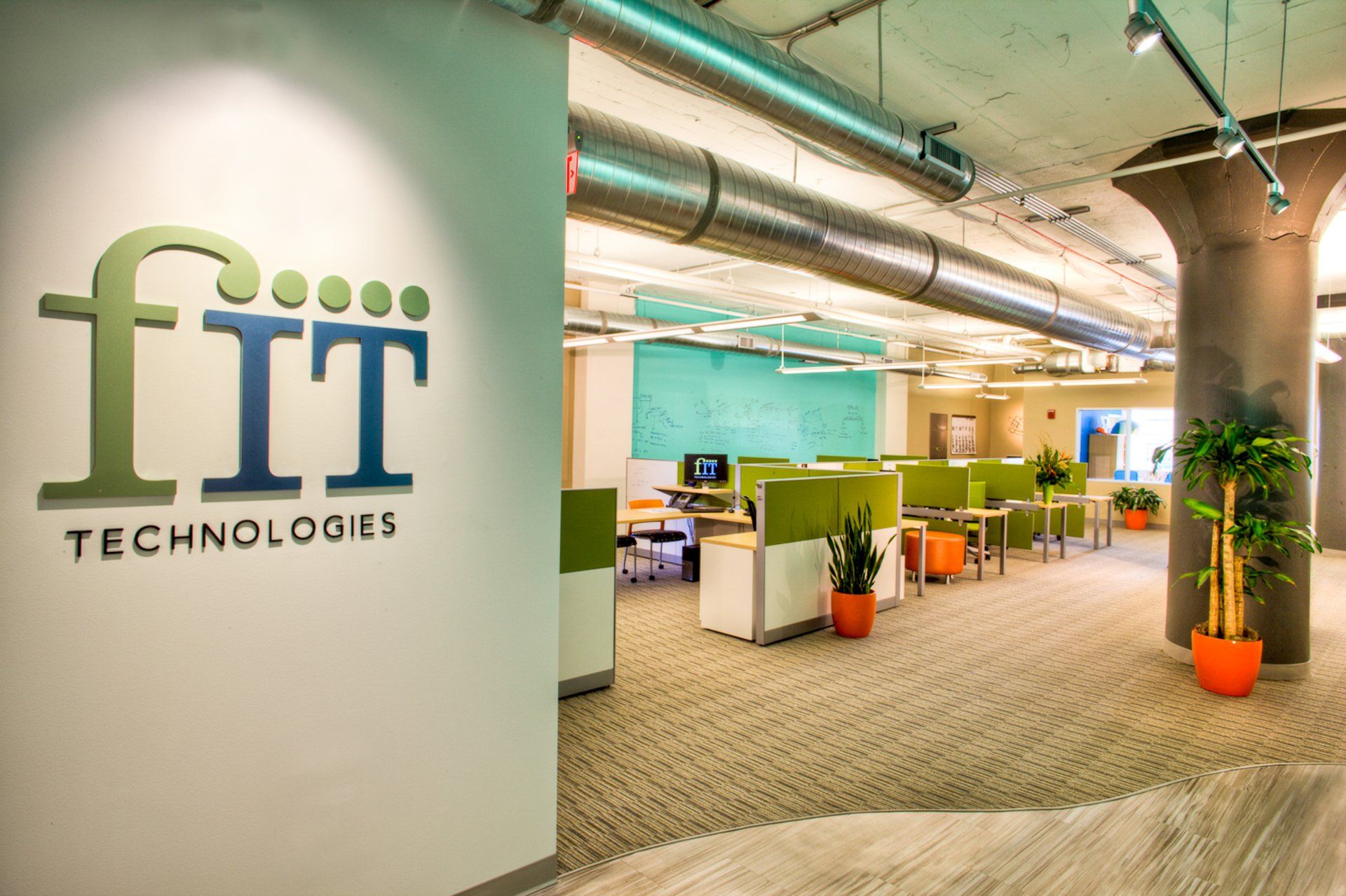 An office with cubicles and a sign that says fit technologies