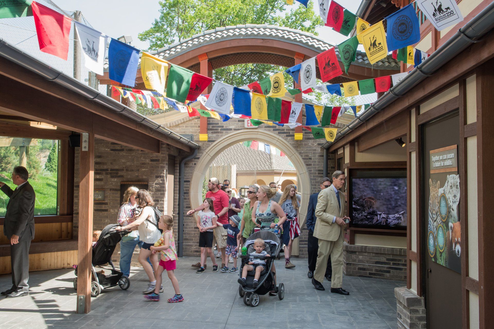 A group of people are walking through a building with flags hanging from the ceiling.