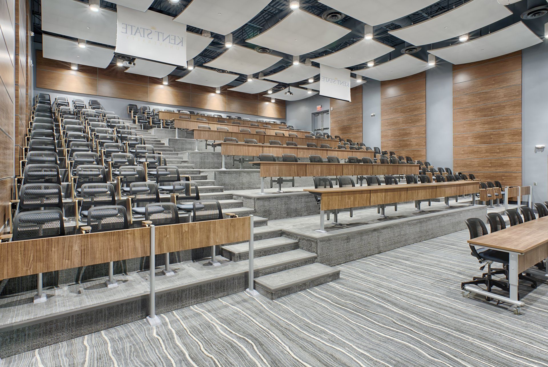 A large lecture hall with tables and chairs in it.
