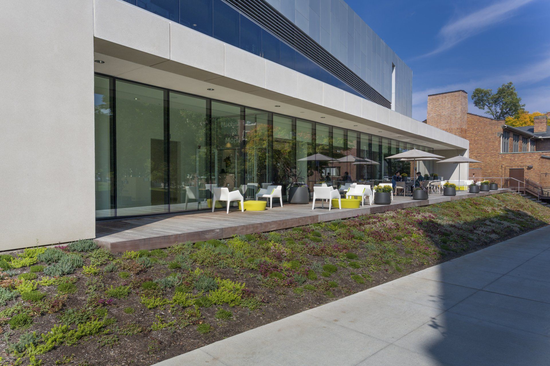 A large building with a lot of windows and a patio with chairs and umbrellas.