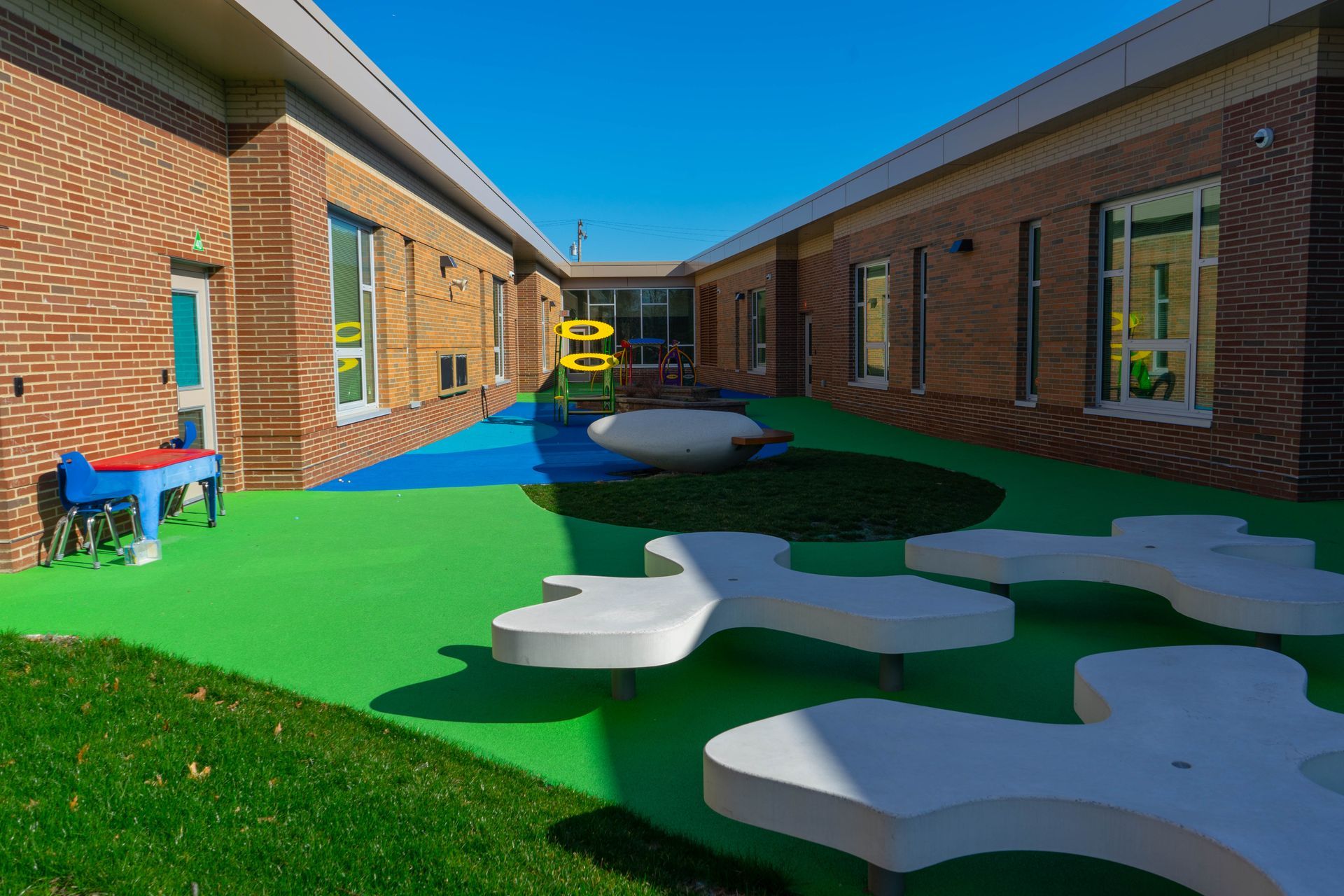 A brick building with a green lawn and white benches in front of it.