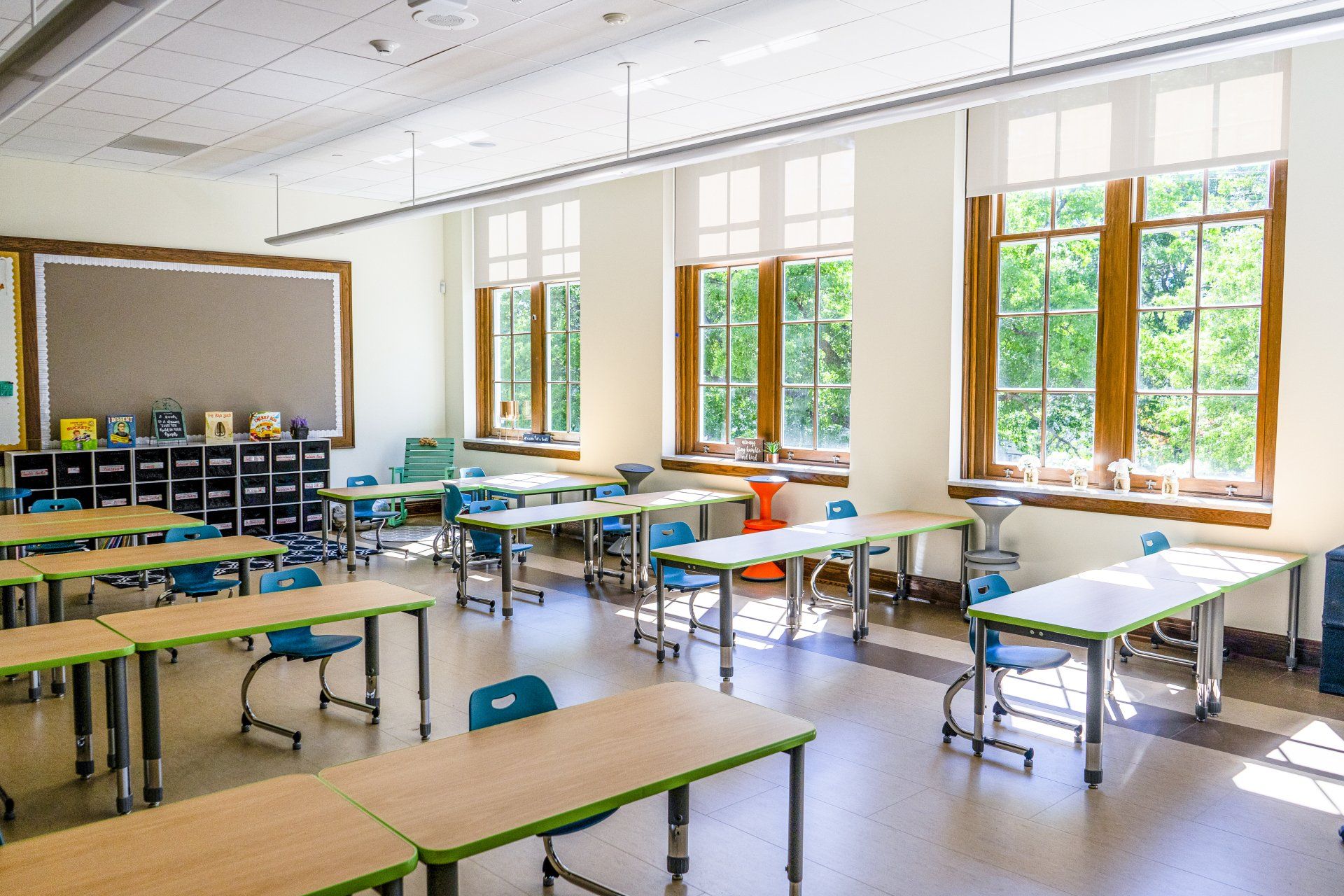 A classroom with tables and chairs and lots of windows.