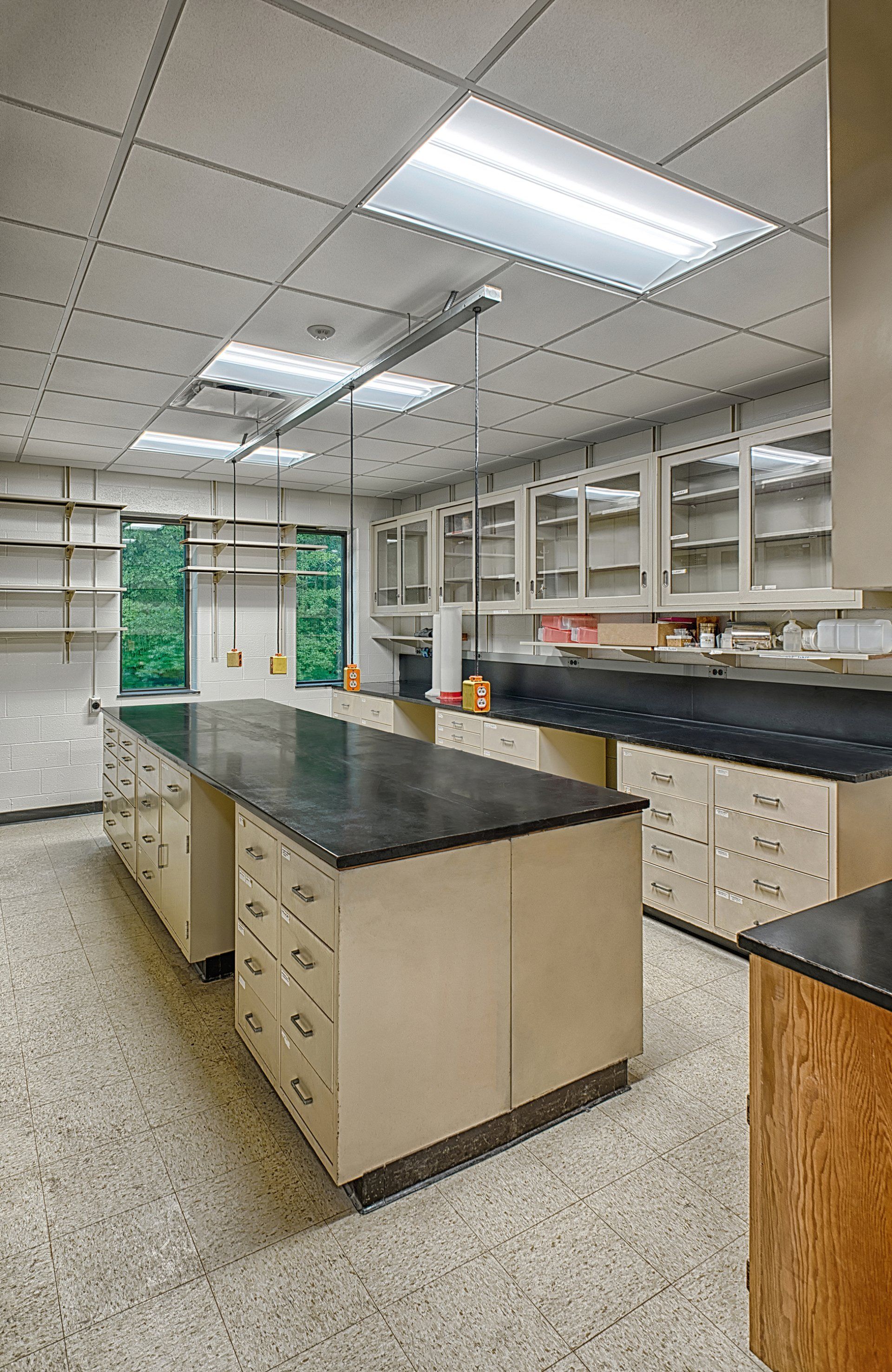 A large empty laboratory with a lot of cabinets and counter tops.