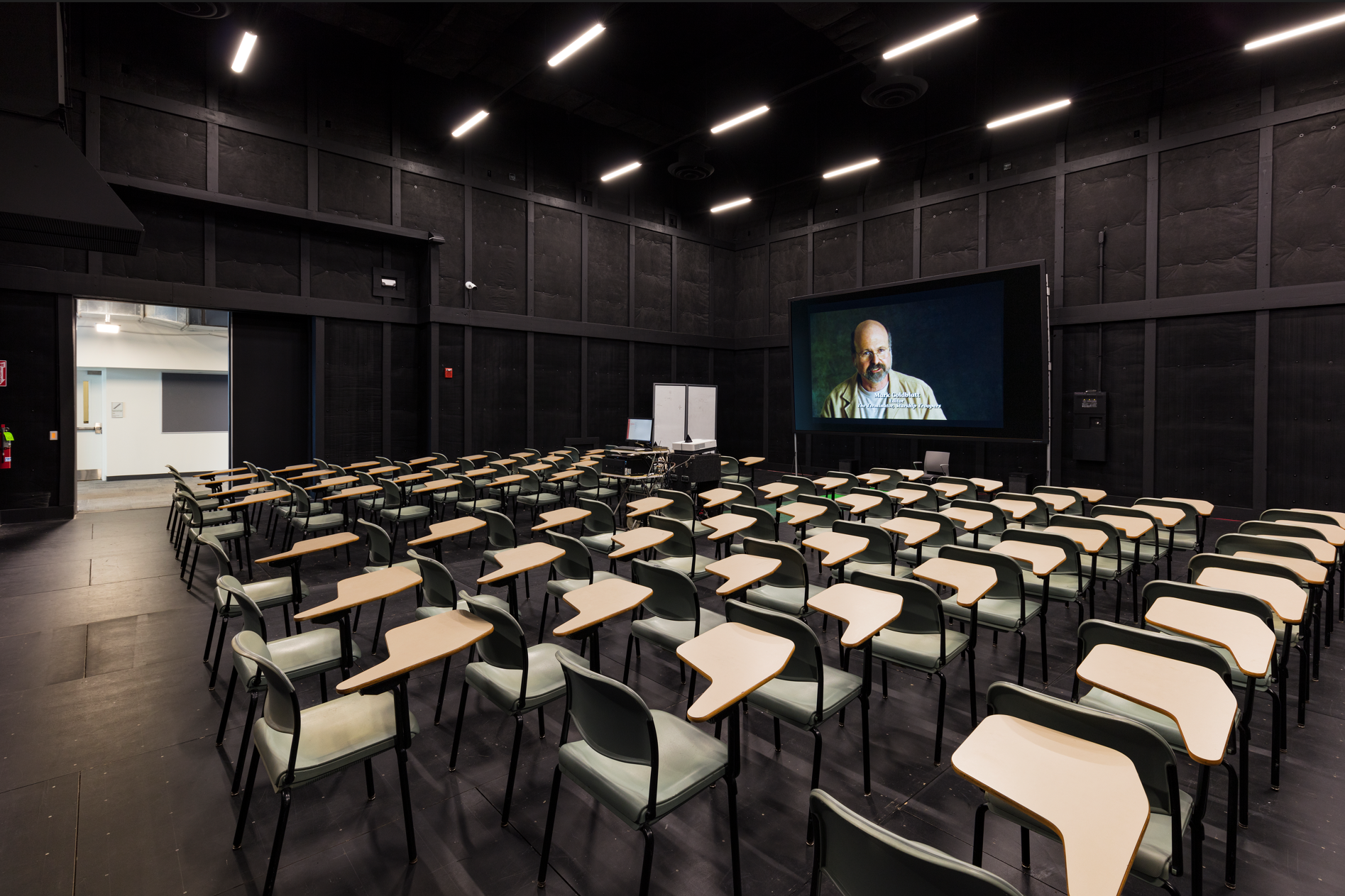 A large auditorium with rows of chairs and a large screen.