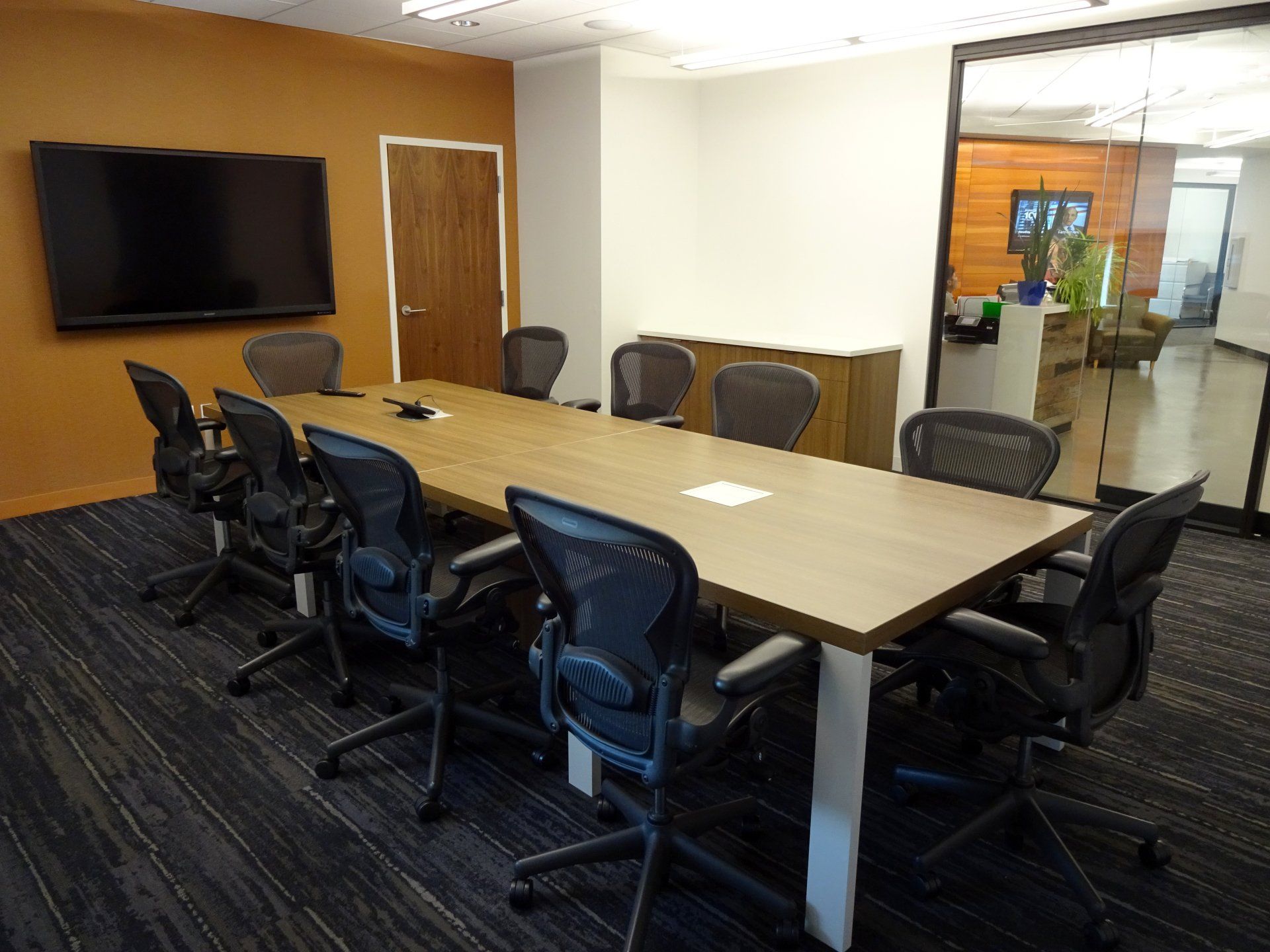 A conference room with a long table and chairs and a flat screen tv.