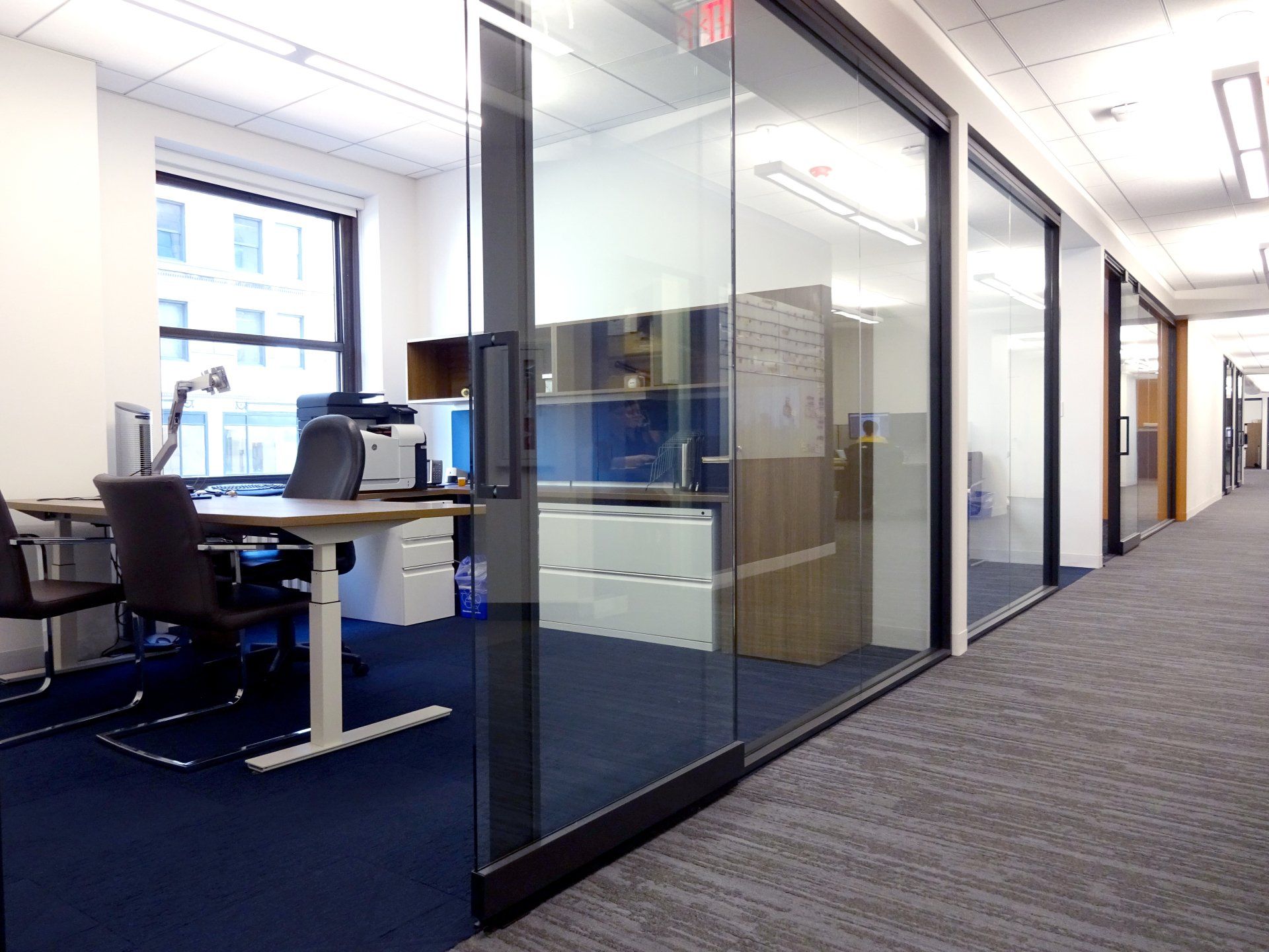 A hallway in an office building with a desk and chairs.