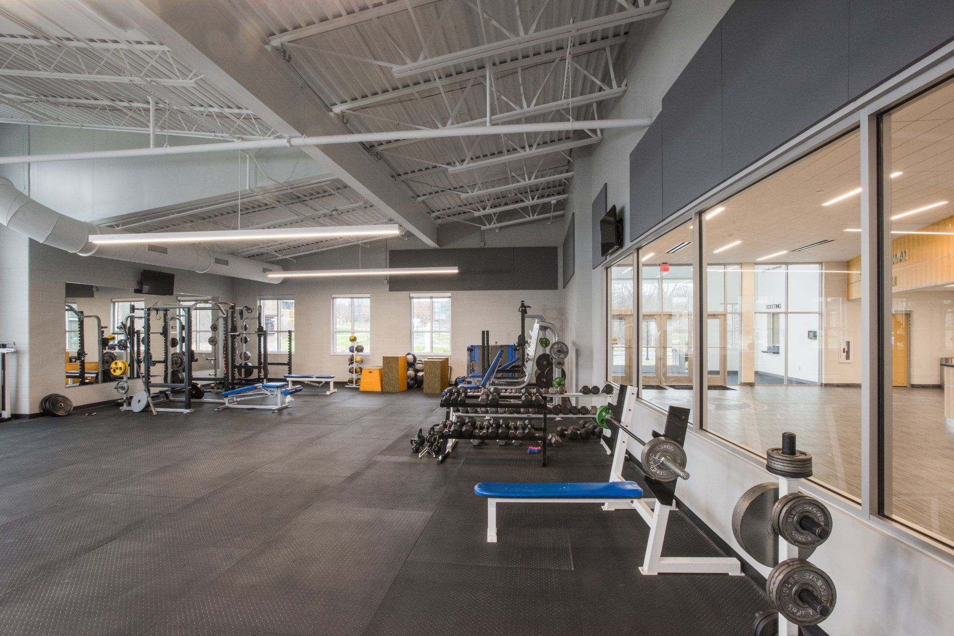 A large gym with a lot of exercise equipment and a bench.