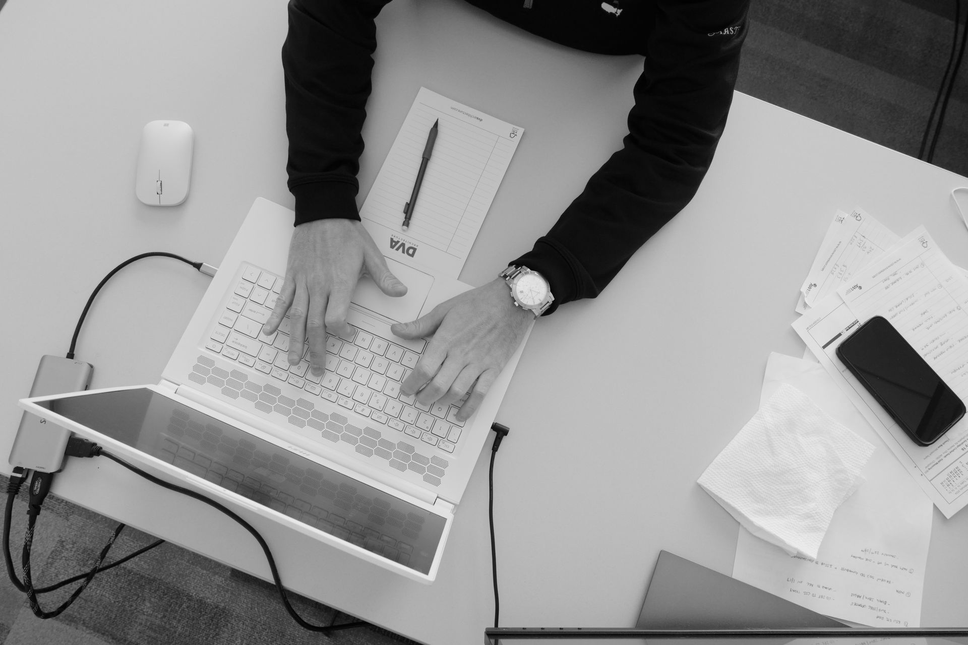 A black and white photo of a person typing on a laptop