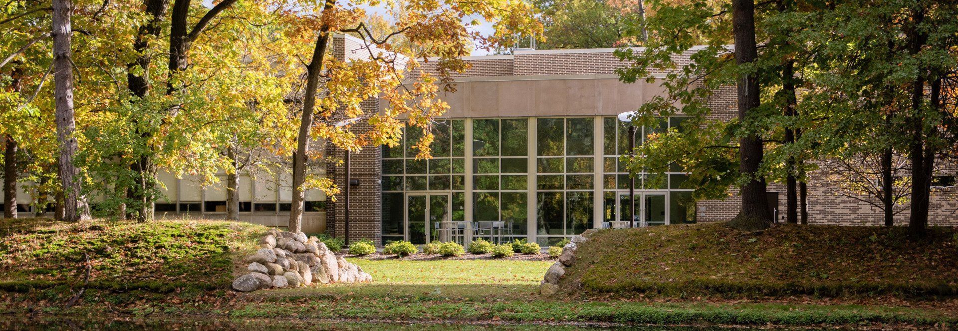A large building with a lot of windows is surrounded by trees in a park.