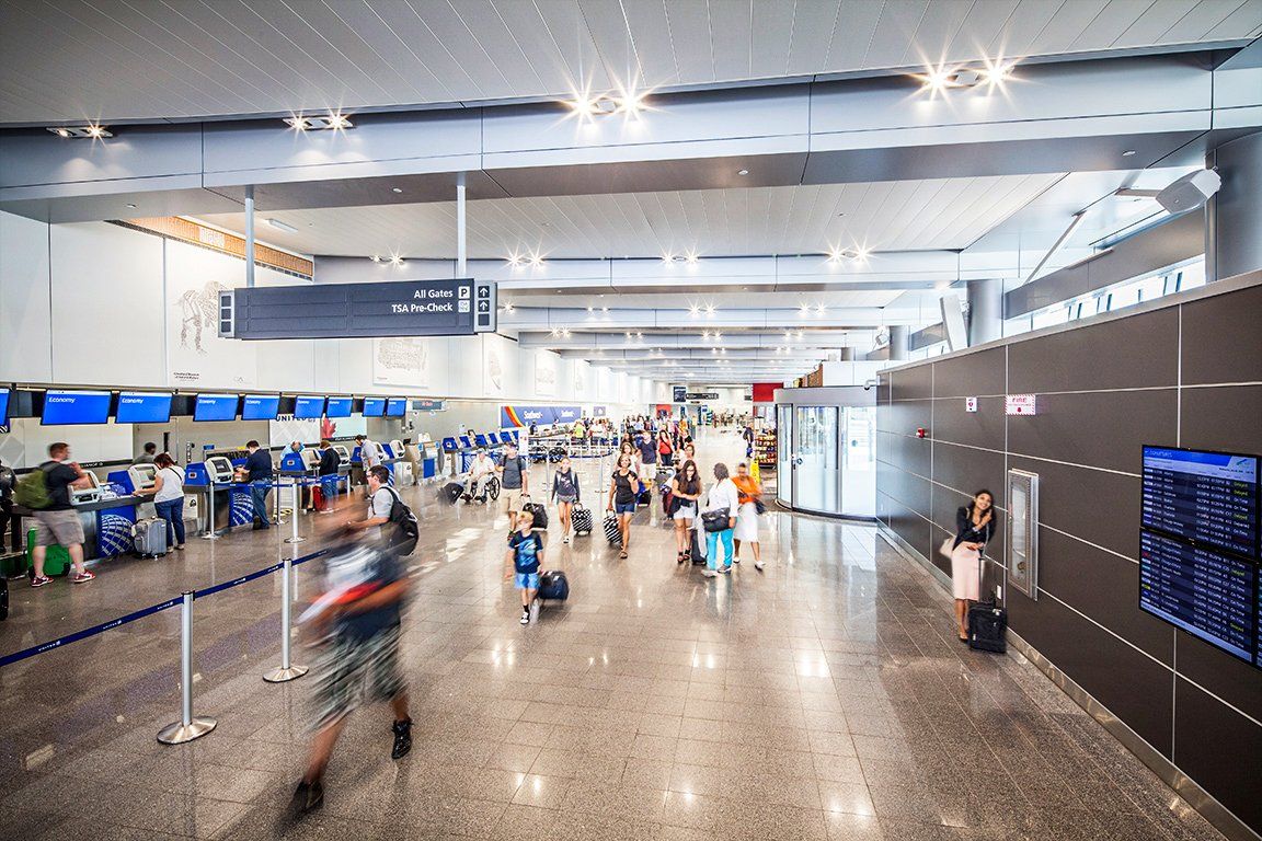 A blurry picture of a crowded airport terminal with people standing and sitting.