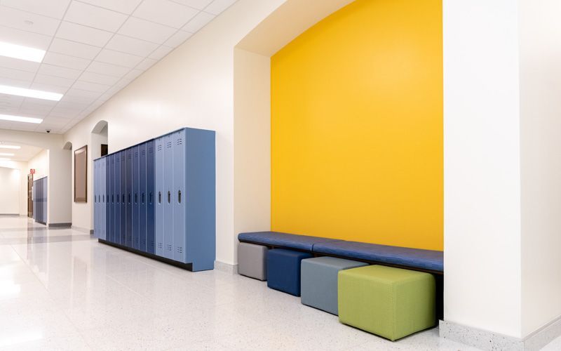 A school hallway with blue lockers and yellow walls.