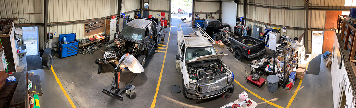 A person using a wrench to tighten a bolt on a metal machine. Hands are dirty. | California Coast Truck Repair