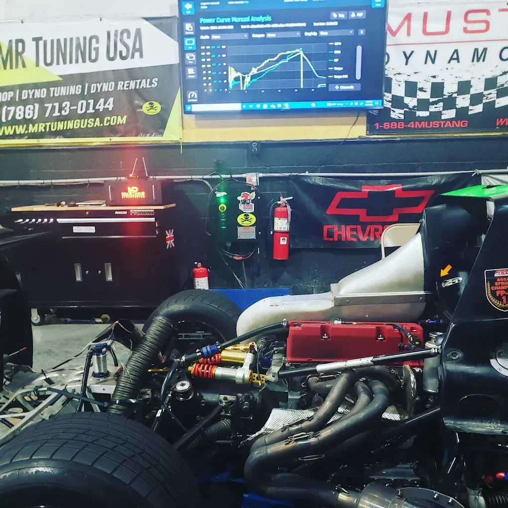 A race car undergoing a dyno test at MR Tuning USA. A computer screen displays performance graphs.