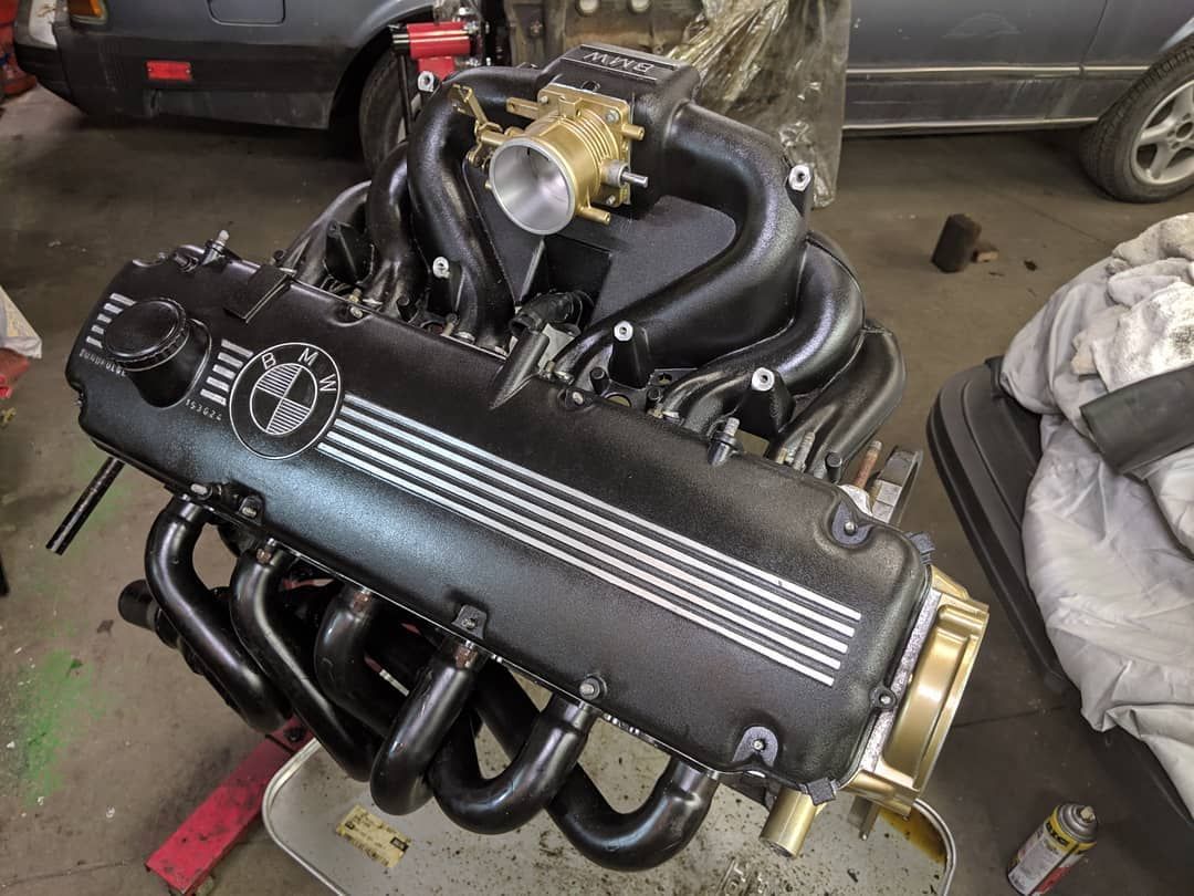 A black bmw engine is sitting on a tray in a garage.