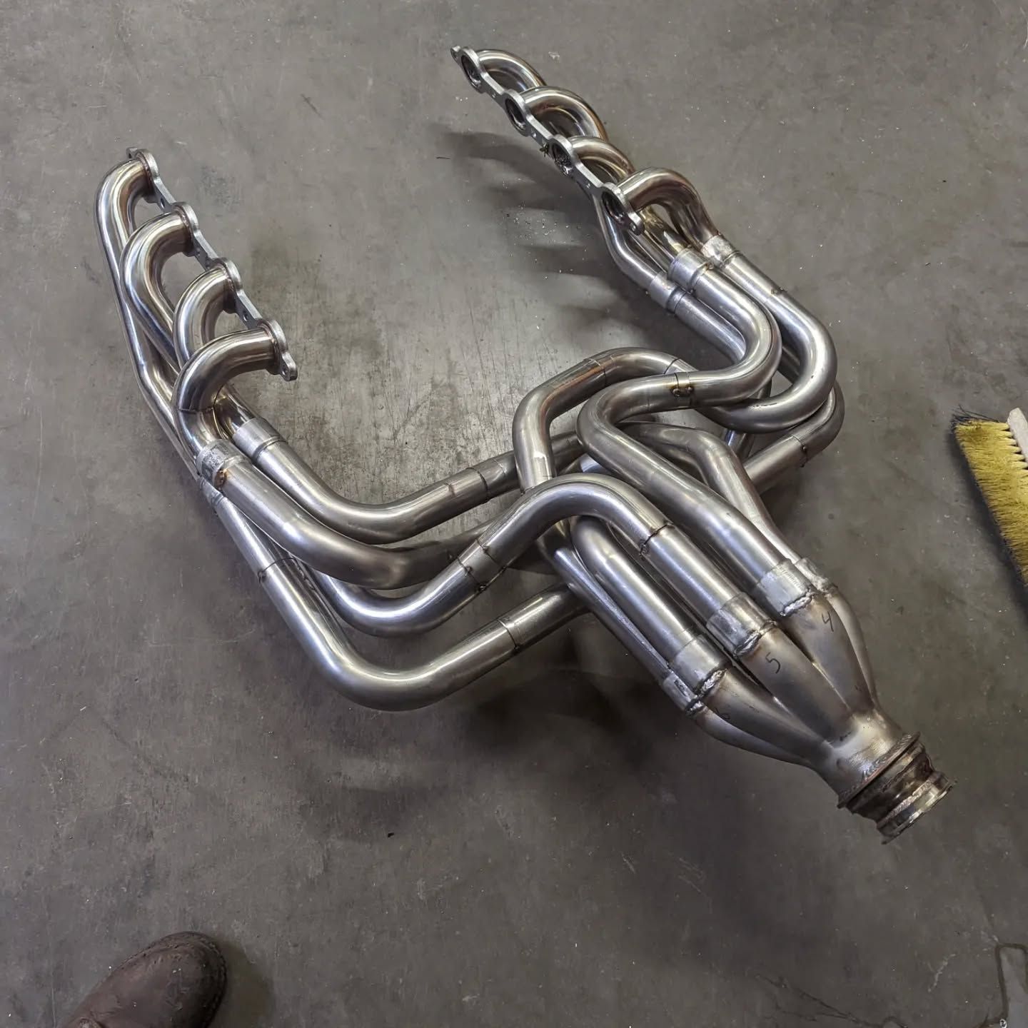 A stainless steel exhaust pipe is laying on the ground