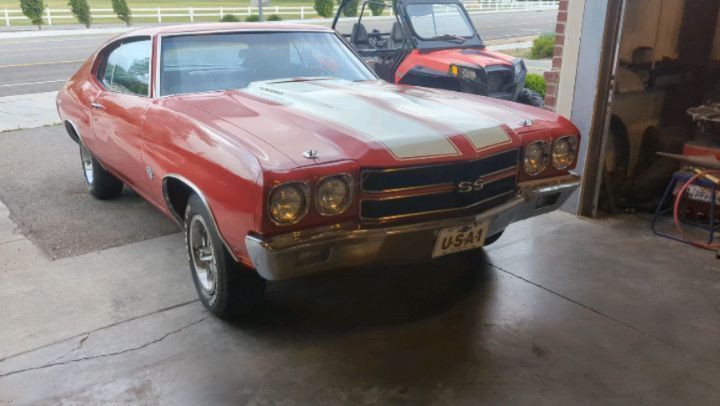A red and white chevrolet chevelle is parked in a garage.