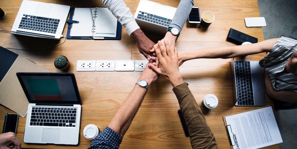 A group of people are putting their hands together on a table.