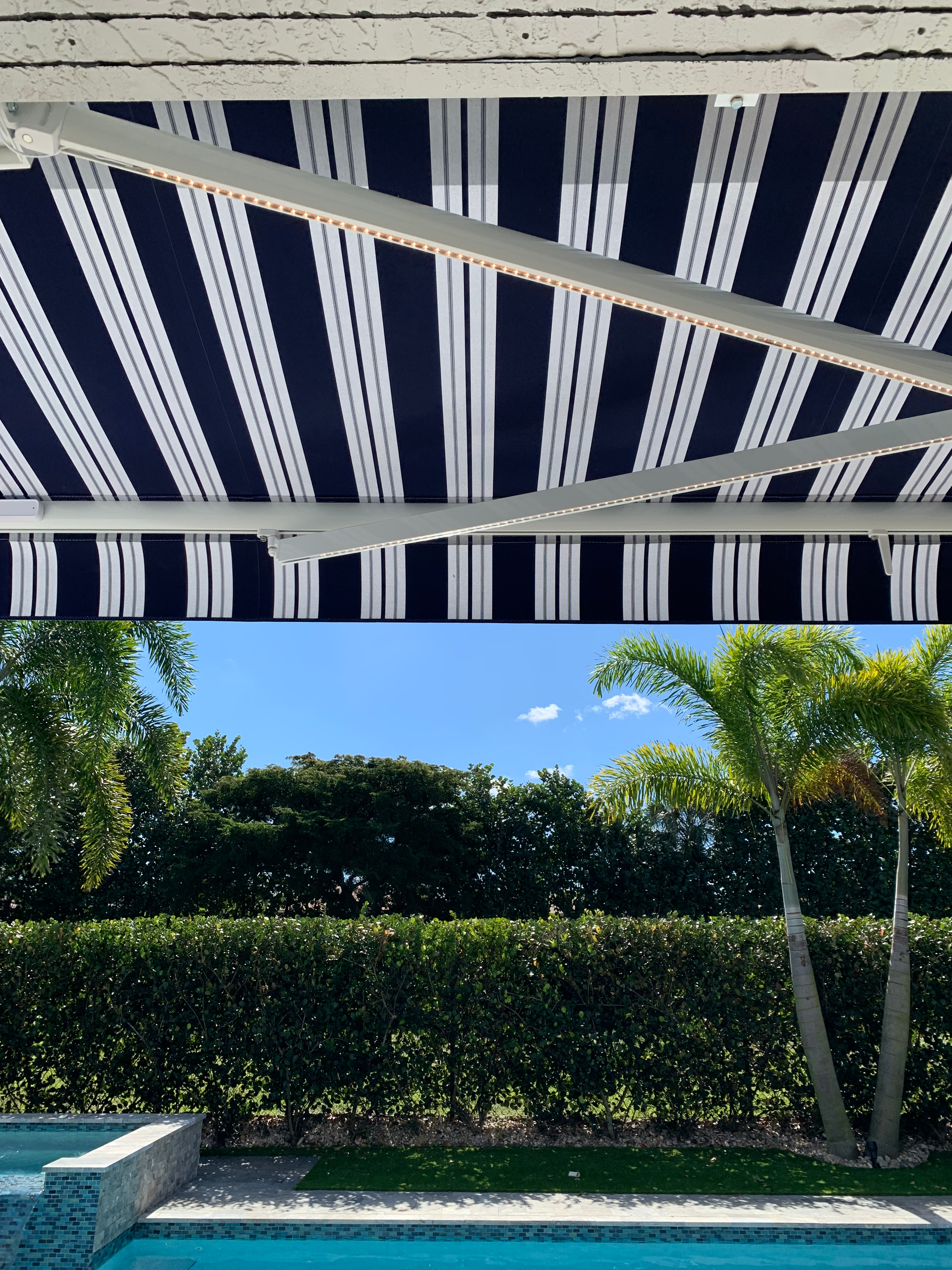 Blue and white striped awning over a pool, with palm trees and hedge visible.