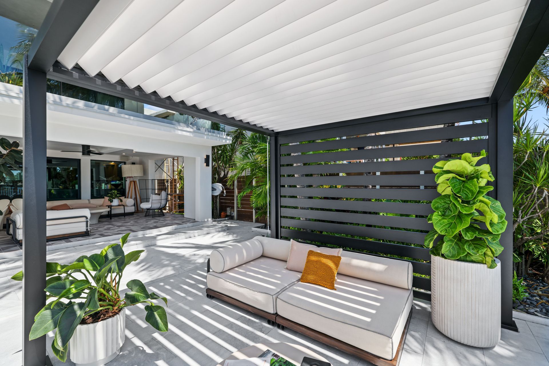 Outdoor patio with a modern pergola, sofa, and potted plants.