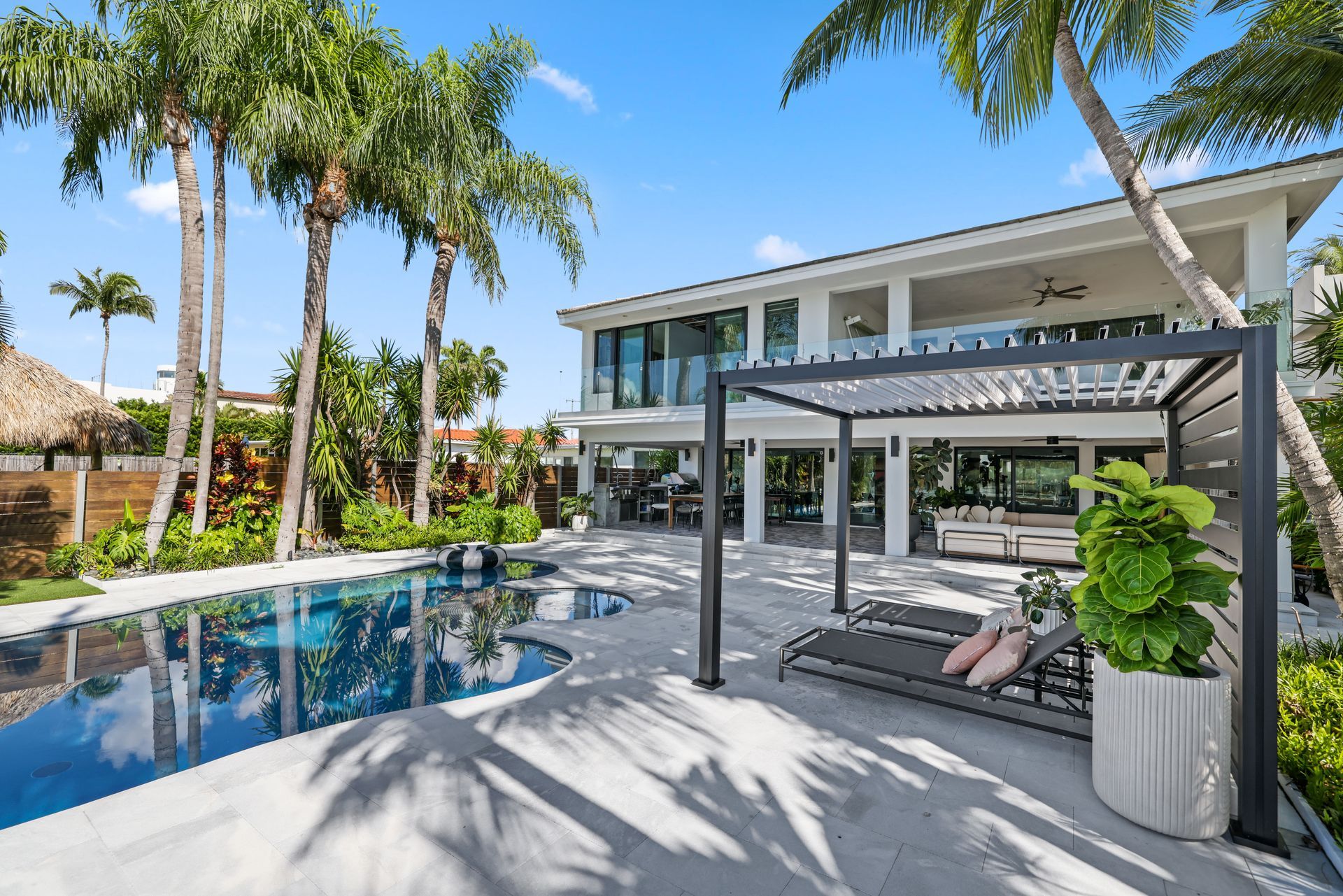 Luxury home backyard with pool, pergola, palm trees, and modern design.