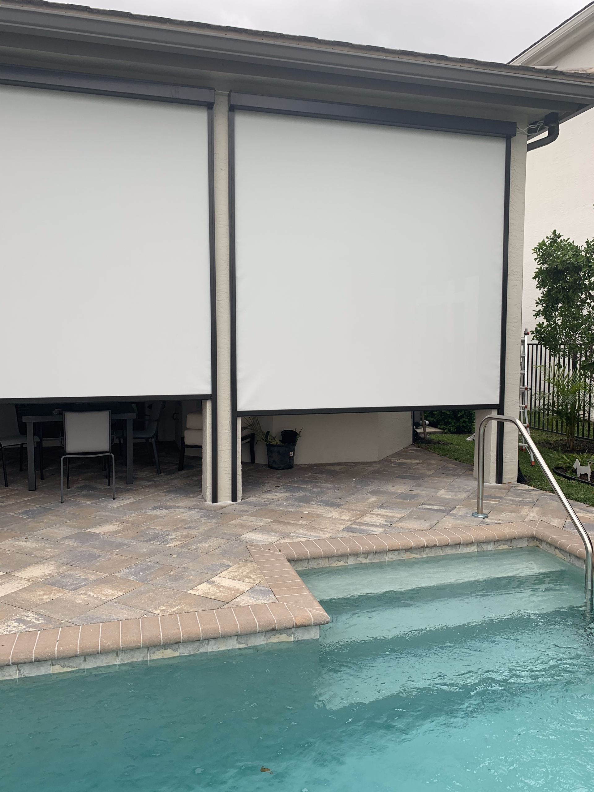 Poolside patio with white sun shades extended down.