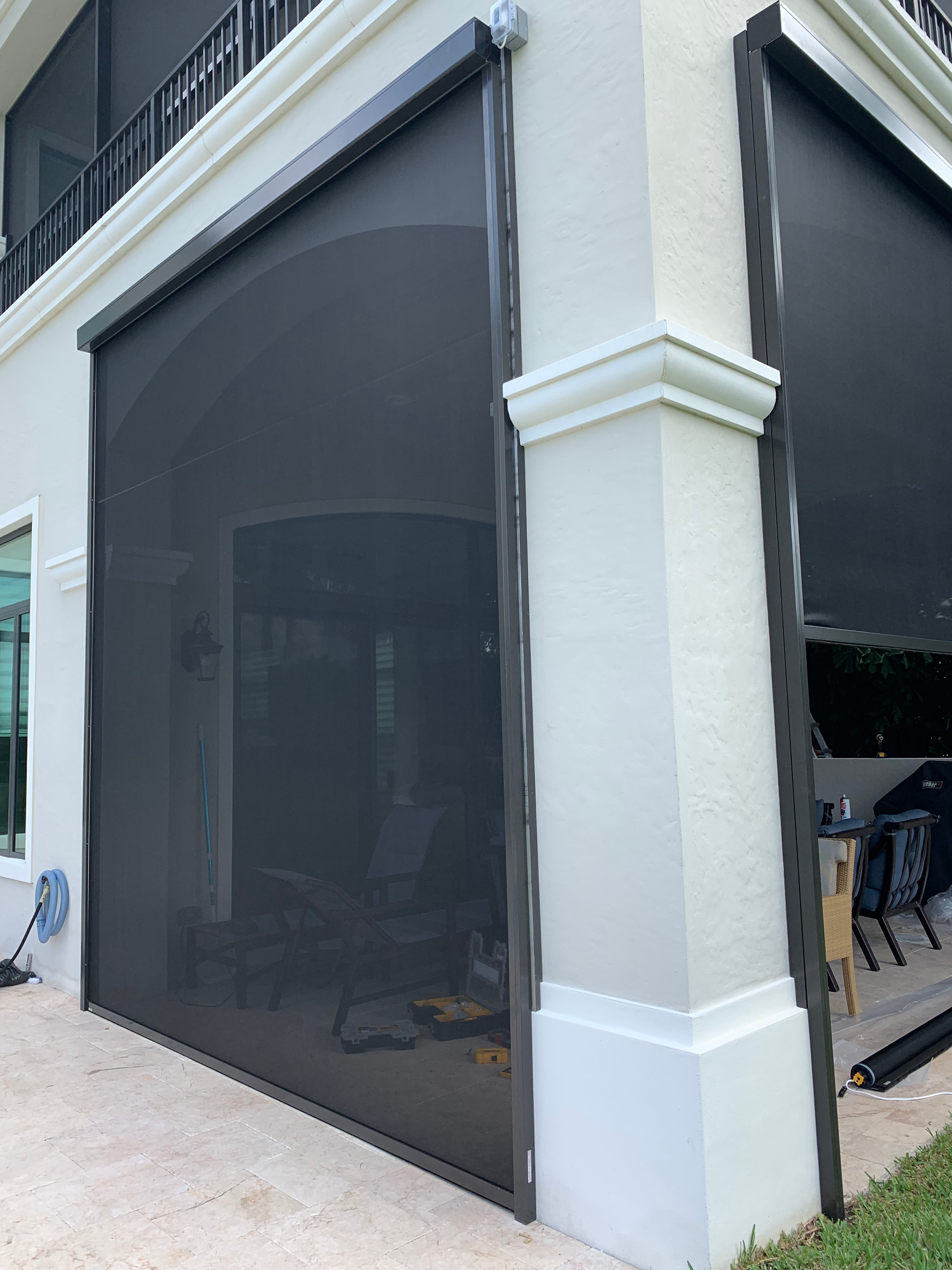 Black retractable outdoor screen on a white building corner.