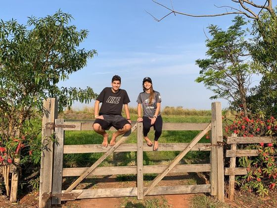 Irmãos sentados na porteira da fazenda.