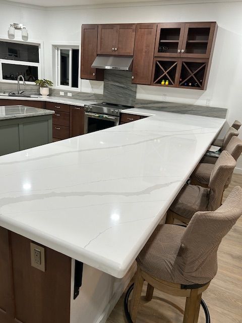A kitchen with a long white counter top and chairs