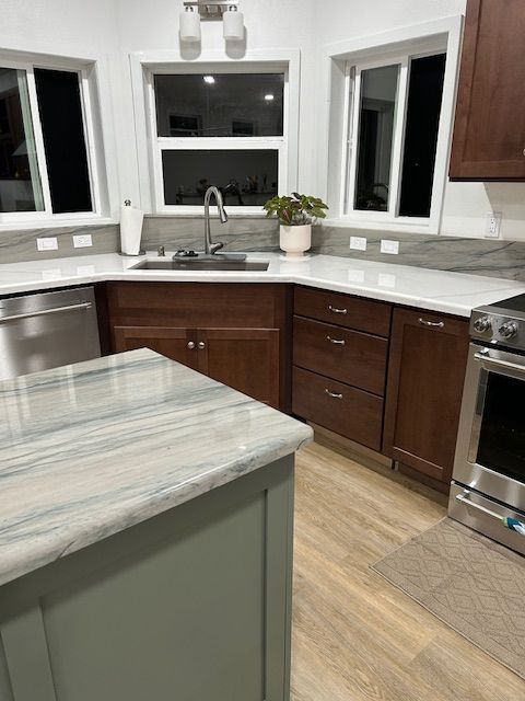 A kitchen with stainless steel appliances , wooden cabinets , granite counter tops , and a large island.
