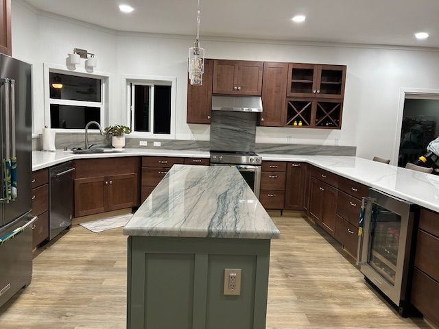 A kitchen with a large island in the middle and stainless steel appliances.