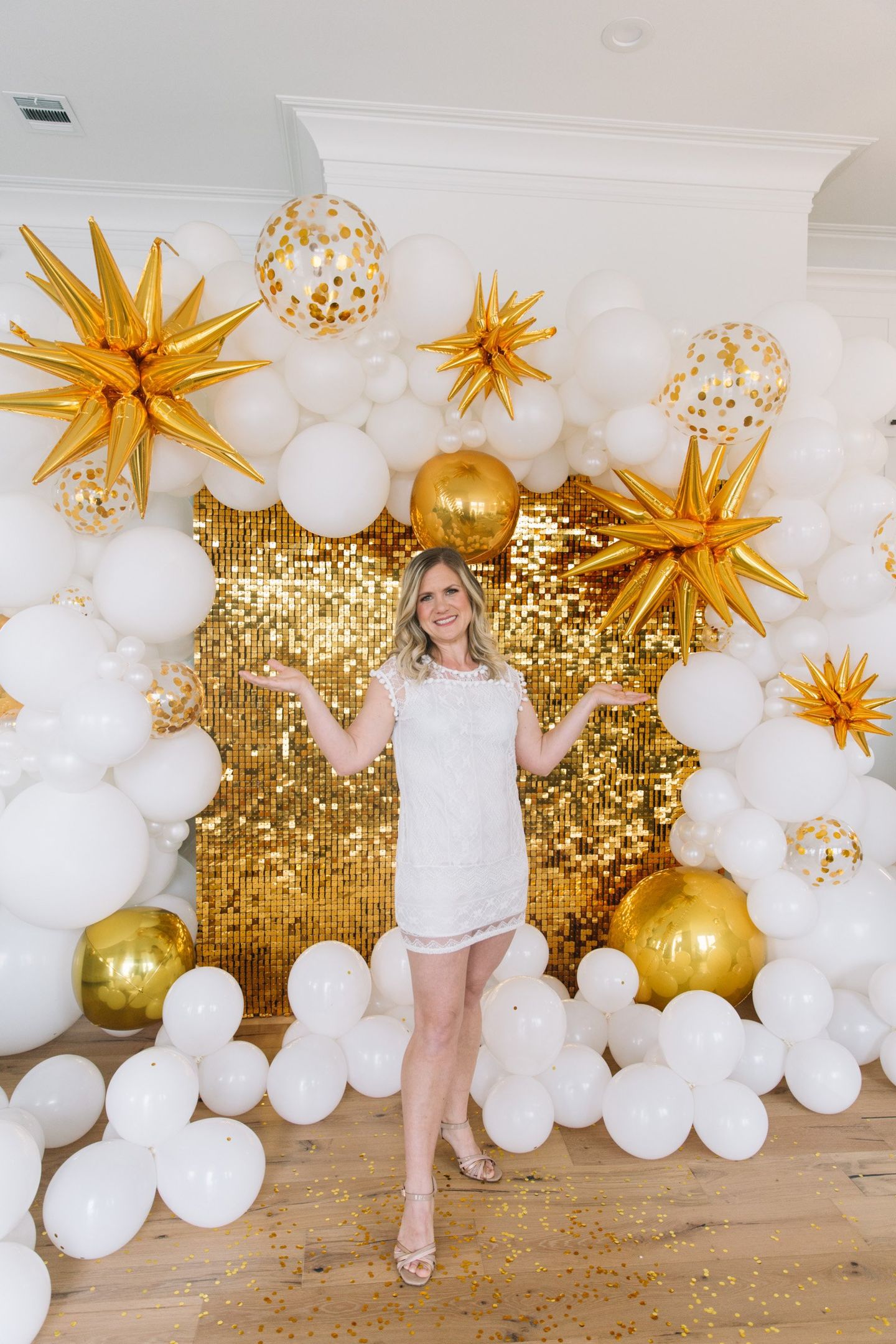 Tabitha Miller with Animated Art Balloons with a gold shimmer wall Backdrop with Organic garland