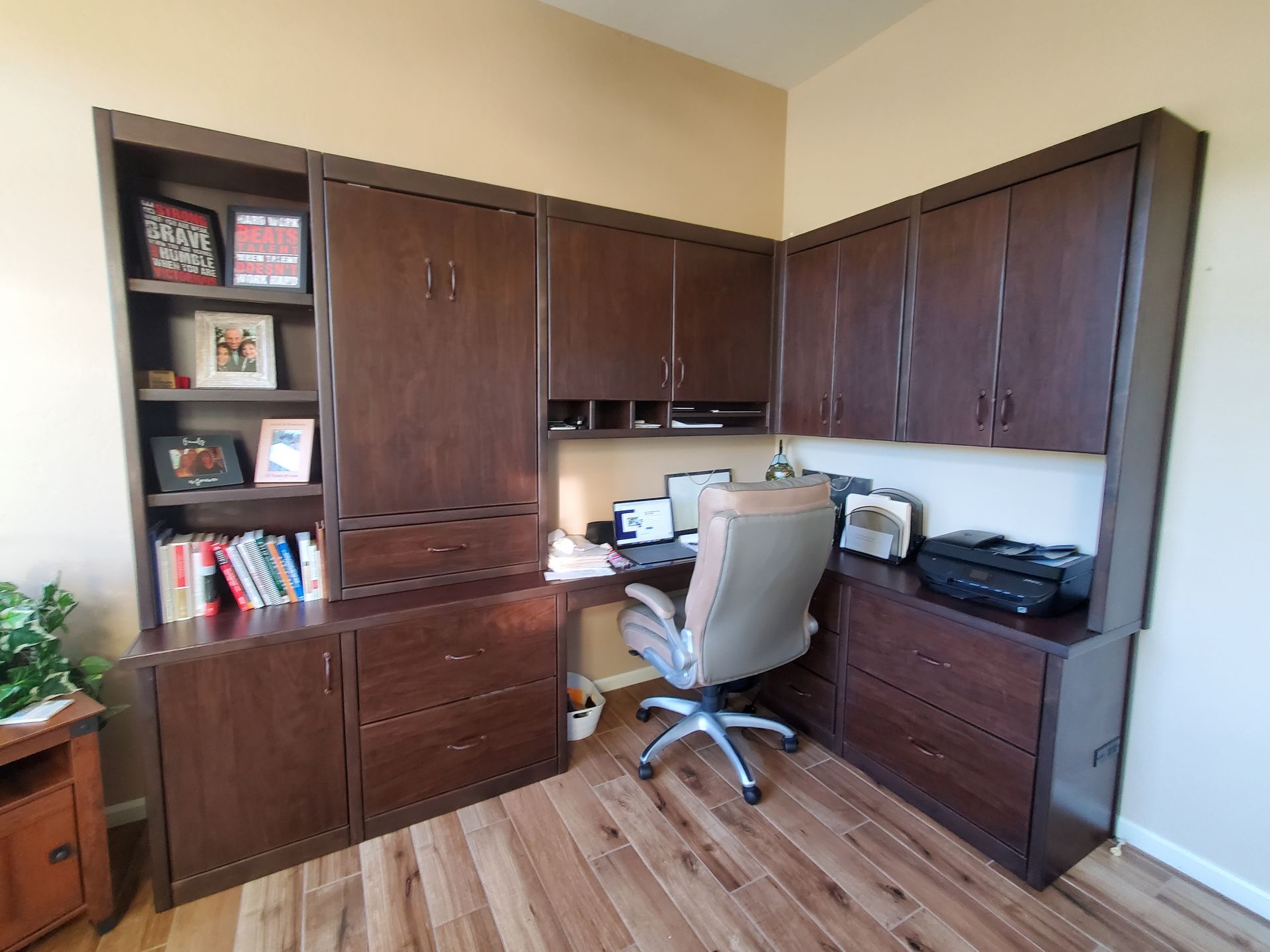 A home office with a desk , chair , shelves and a printer.