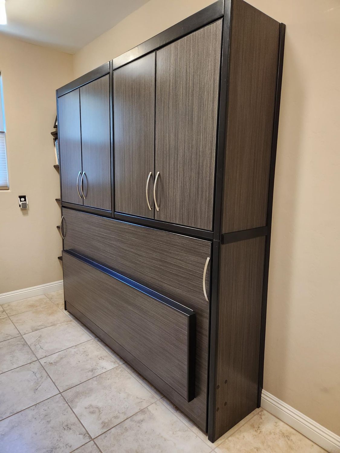 A large wooden cabinet is sitting in a room next to a window.