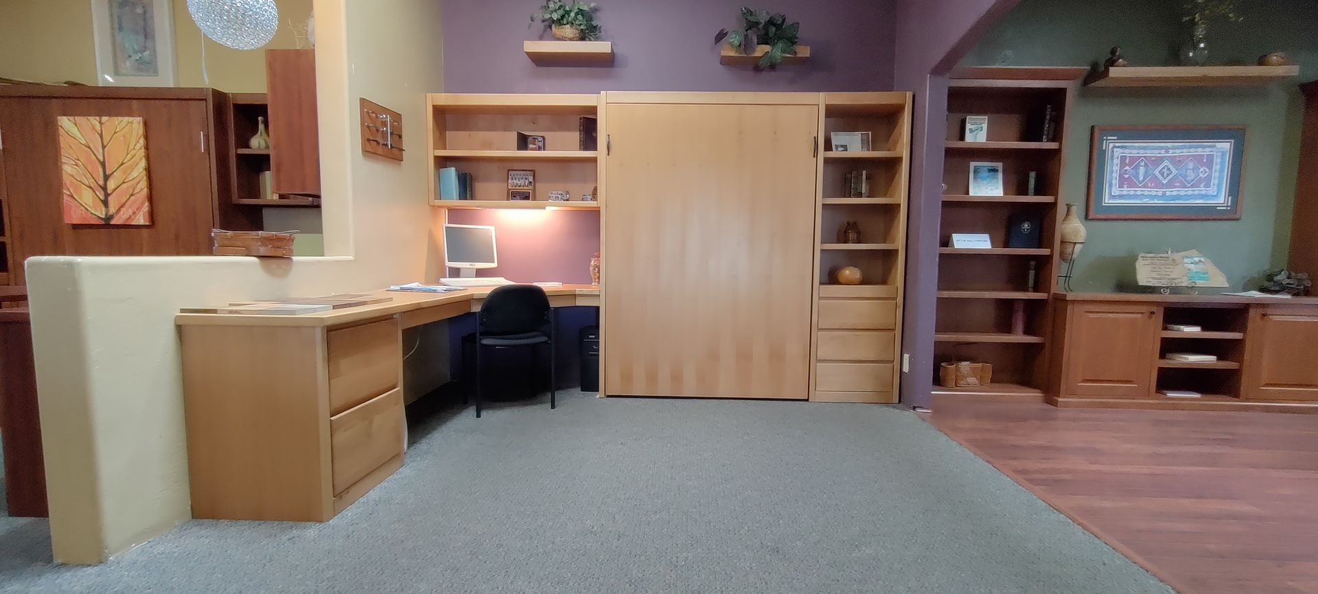 A room with a purple wall and a desk with a computer on it