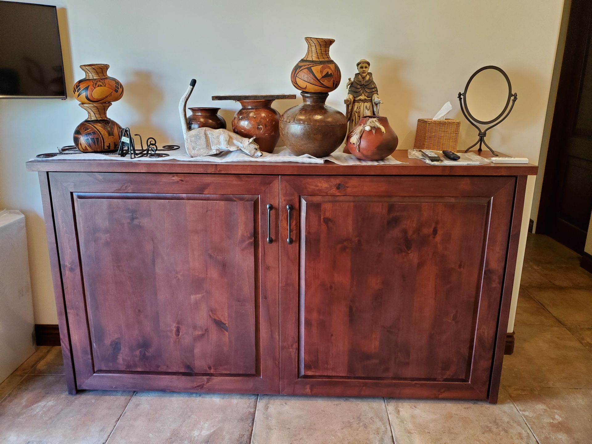 A wooden cabinet with vases and a mirror on top of it.