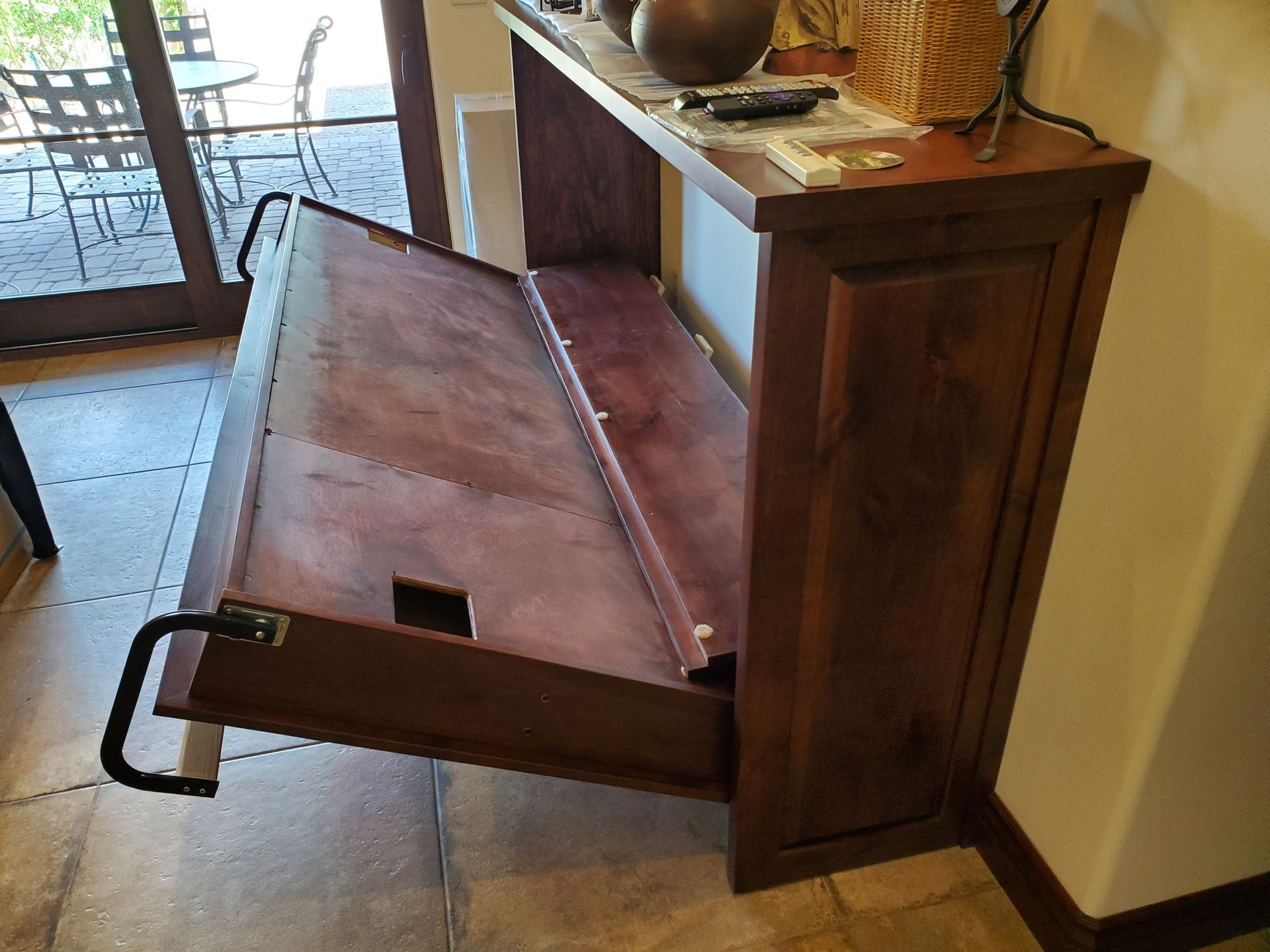 A wooden cabinet with the door open in a room.