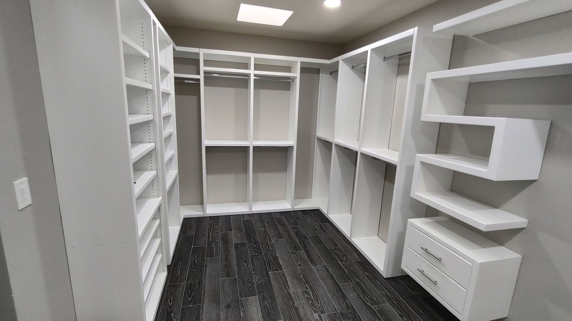 A large walk in closet with lots of shelves and drawers.