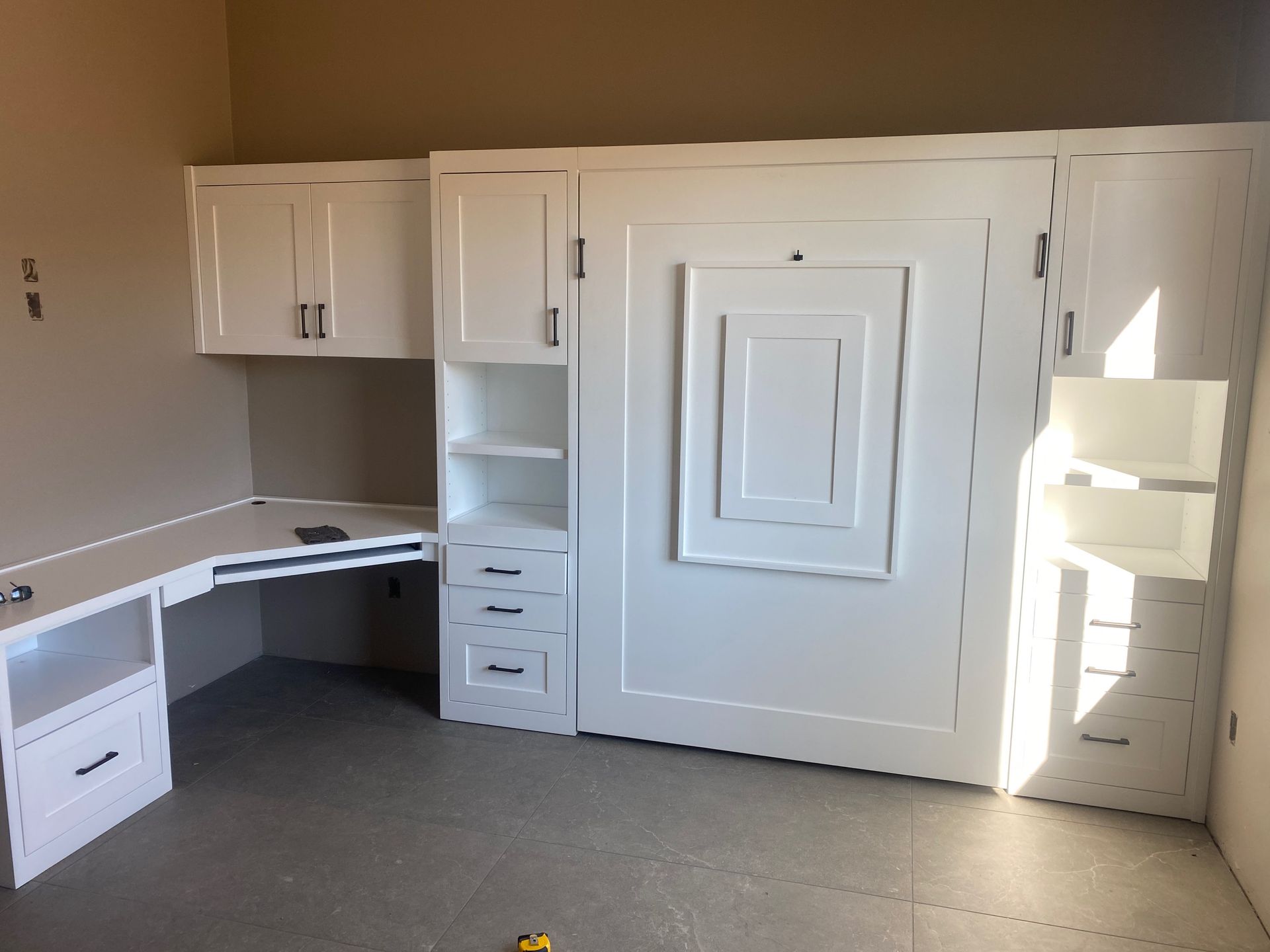 A room with a wall mounted bed and a desk