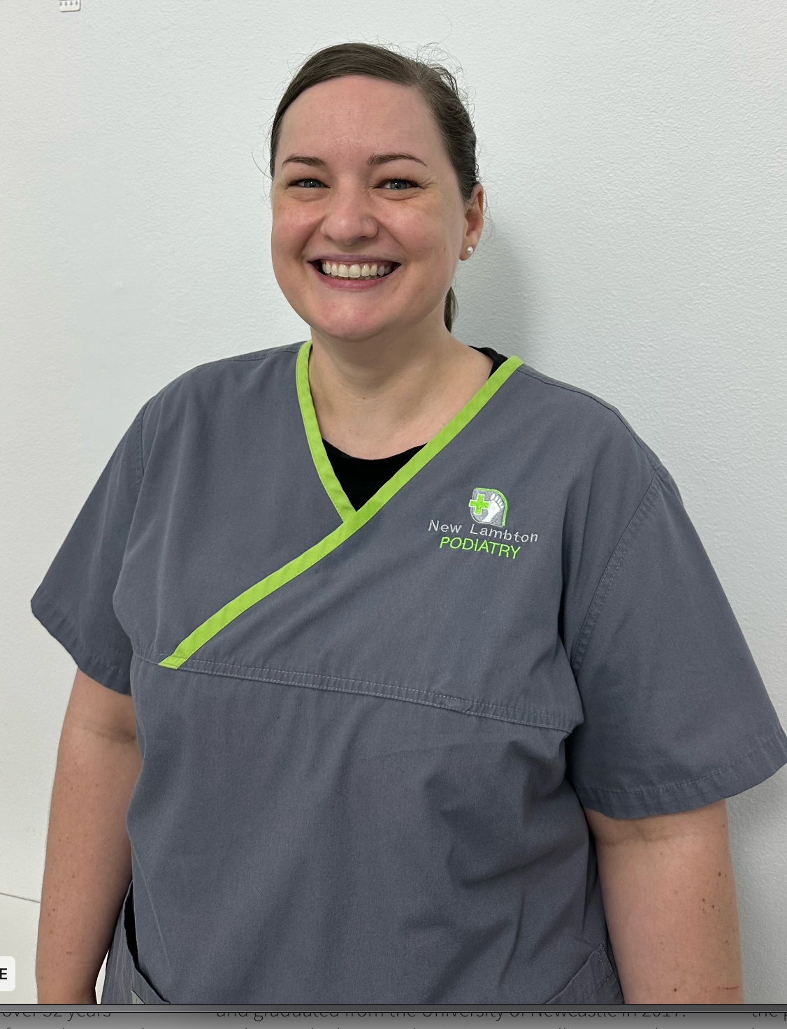 A woman in a gray scrub top is smiling for the camera.