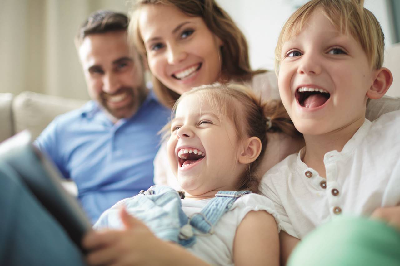 A family posing with their kids while having a laugh