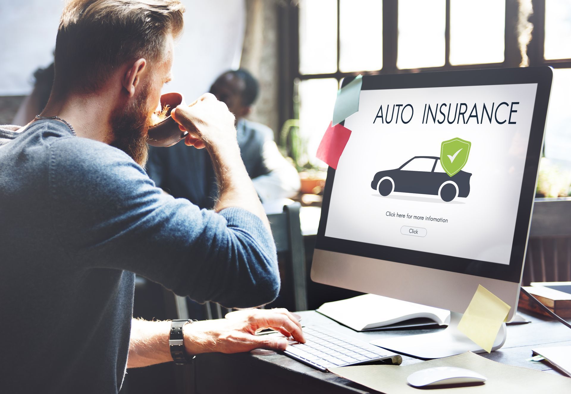 Man looking at auto insurance on a computer screen while drinking coffee.