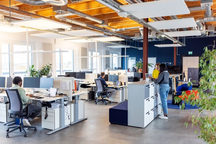 A group of people are sitting at desks in an office.