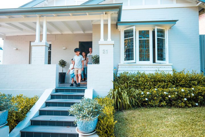 A family is standing on the porch of a white house.