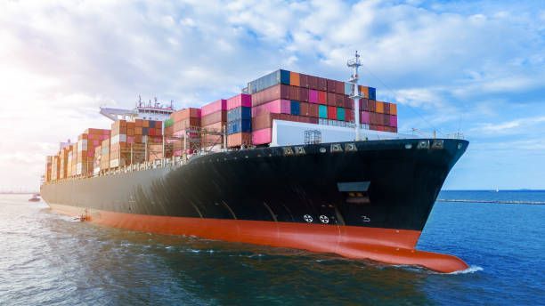 Cargo ship sailing on the ocean, loaded with shipping containers, blue sky.