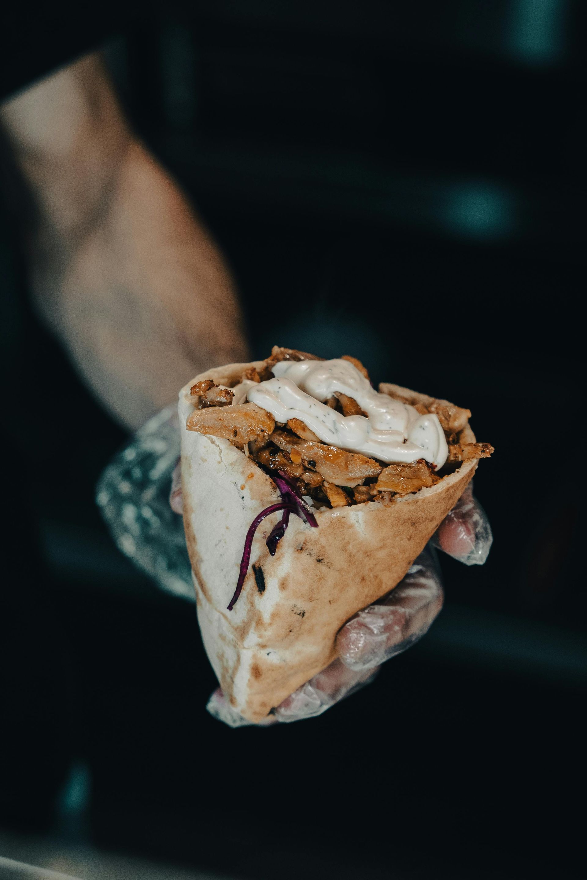 Hand holding a wrap filled with meat, cabbage, and sauce.